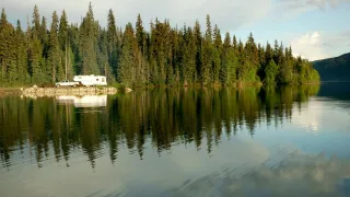 Camper on the shore of a northern lake surrounded by trees