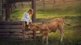 Girl sitting by a well, petting a calf.