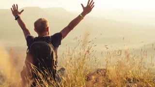 guy in field with arms raised