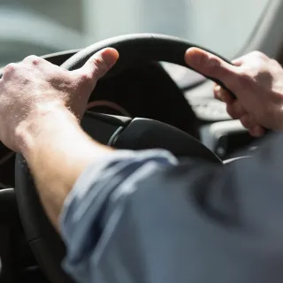 Close-up of hands holding a steering wheel.