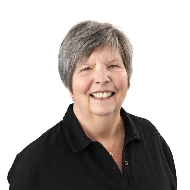 Smiling elderly woman wearing a black button-down shirt.