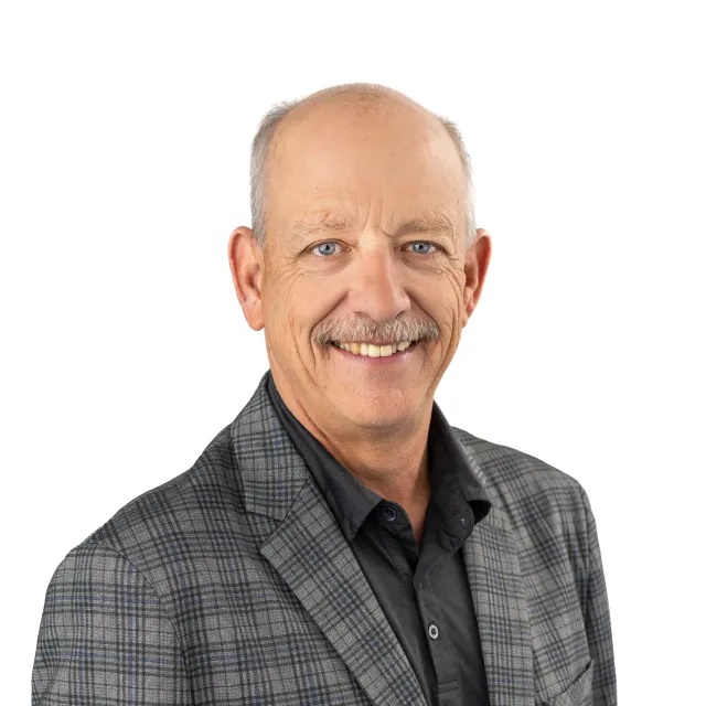 Smiling, older man wearing a checkered sport coat.